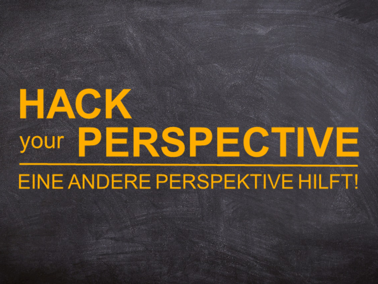 hack-your-perspektive Schwarze Tafel mit dem Text "Hack your Perspective" in orange und der deutschen Übersetzung.