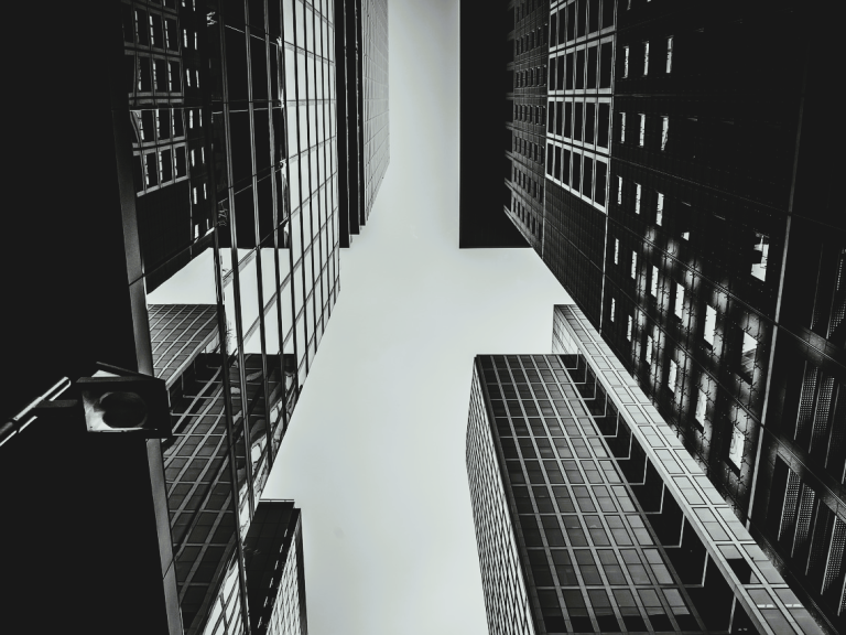 Business Firma Blick nach oben zwischen hohen, modernen Gebäuden in Schwarz-Weiß.