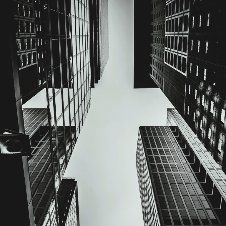 Business_Firma Blick nach oben zwischen hohen Gebäuden in Schwarz-Weiß.